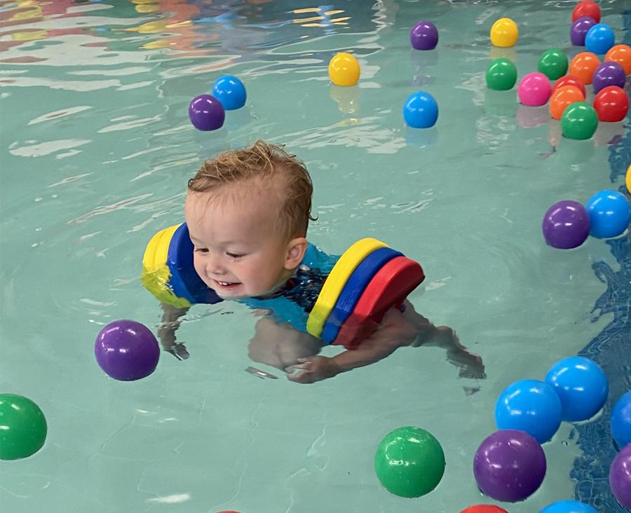 Toddler playing with colourful balls in the Making Waves pool